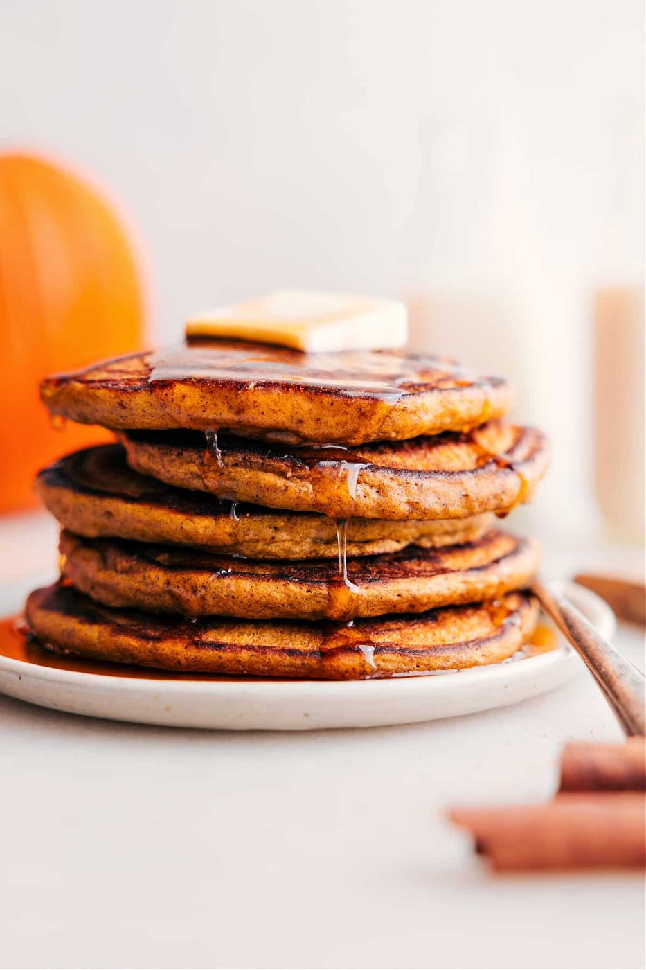 Pumpkin spice desserts featuring a stack of pumpkin pancakes topped with butter and drizzled with syrup.