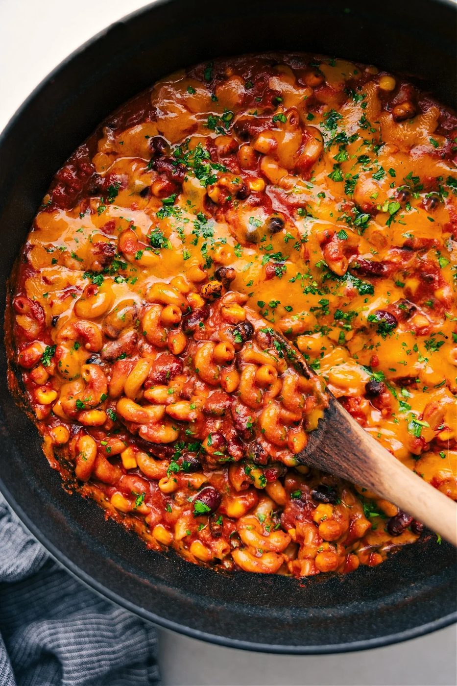 Vegetarian recipes: vegetarian chili mac in a pot with melted cheese on top and a big scoop being served.