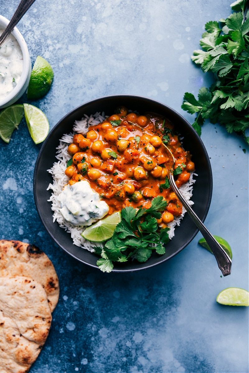 Vegetarian recipes: Chickpea curry in a bowl with creamy sauce, garnished with cilantro and lime wedges.