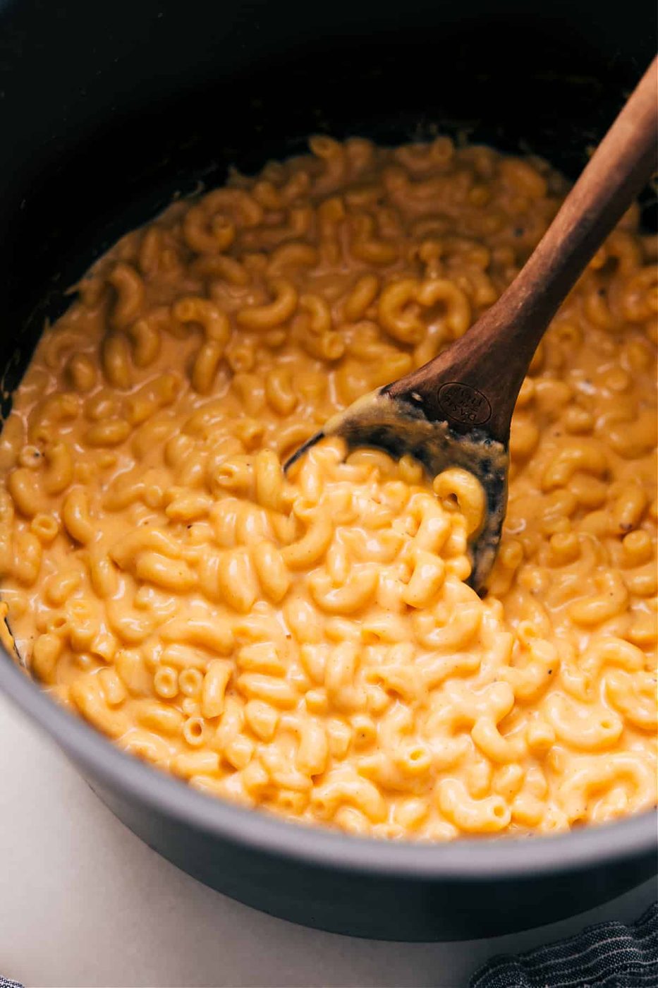 The mac and cheese in a pot with a spoon scooping some out.