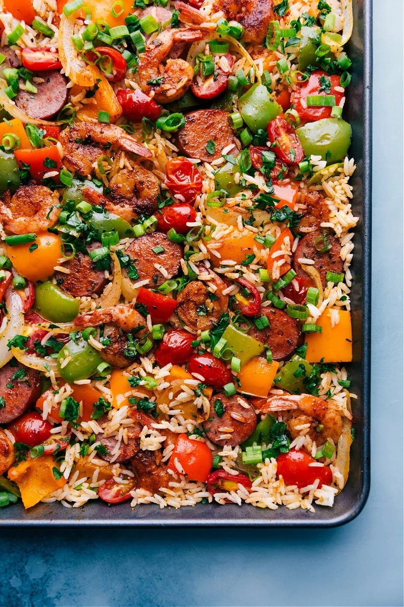 One pan jambalaya on a sheet pan with seasoned sausage, shrimp, veggies, and rice.