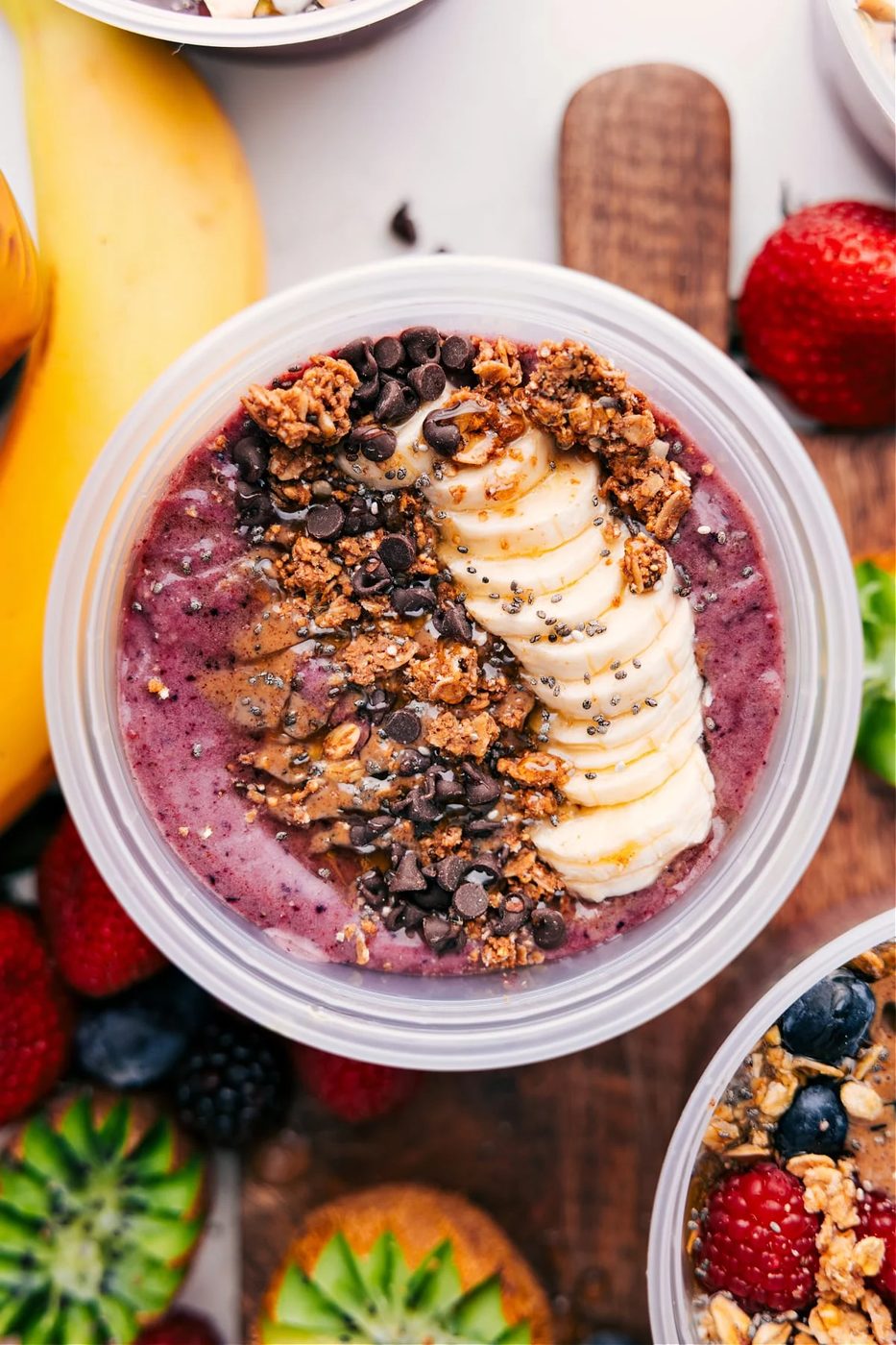 Peanut butter chocolate smoothie bowl topped with granola, bananas, peanut butter, chocolate chips, and honey.