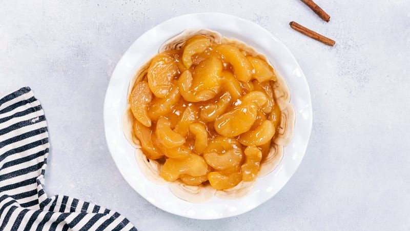The apple filling being added to the crust.