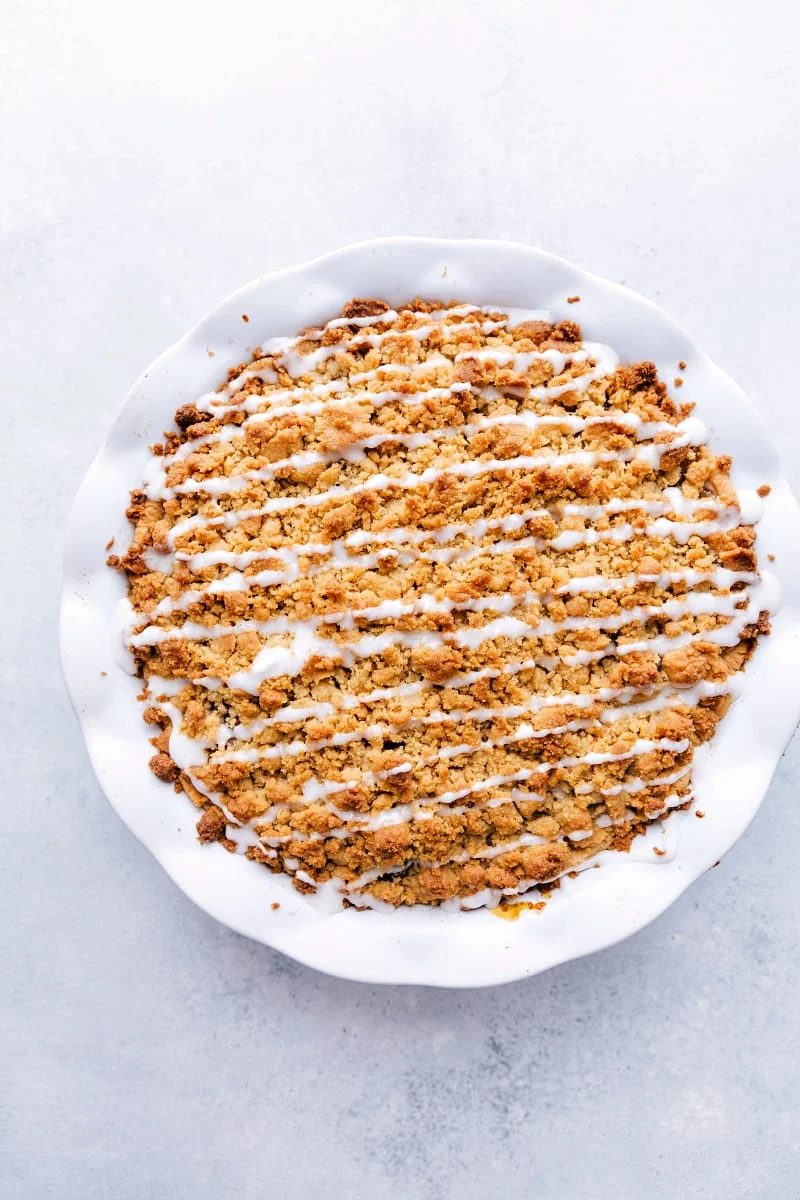 Cinnamon Roll Apple Pie in a pie pan drizzled with icing.