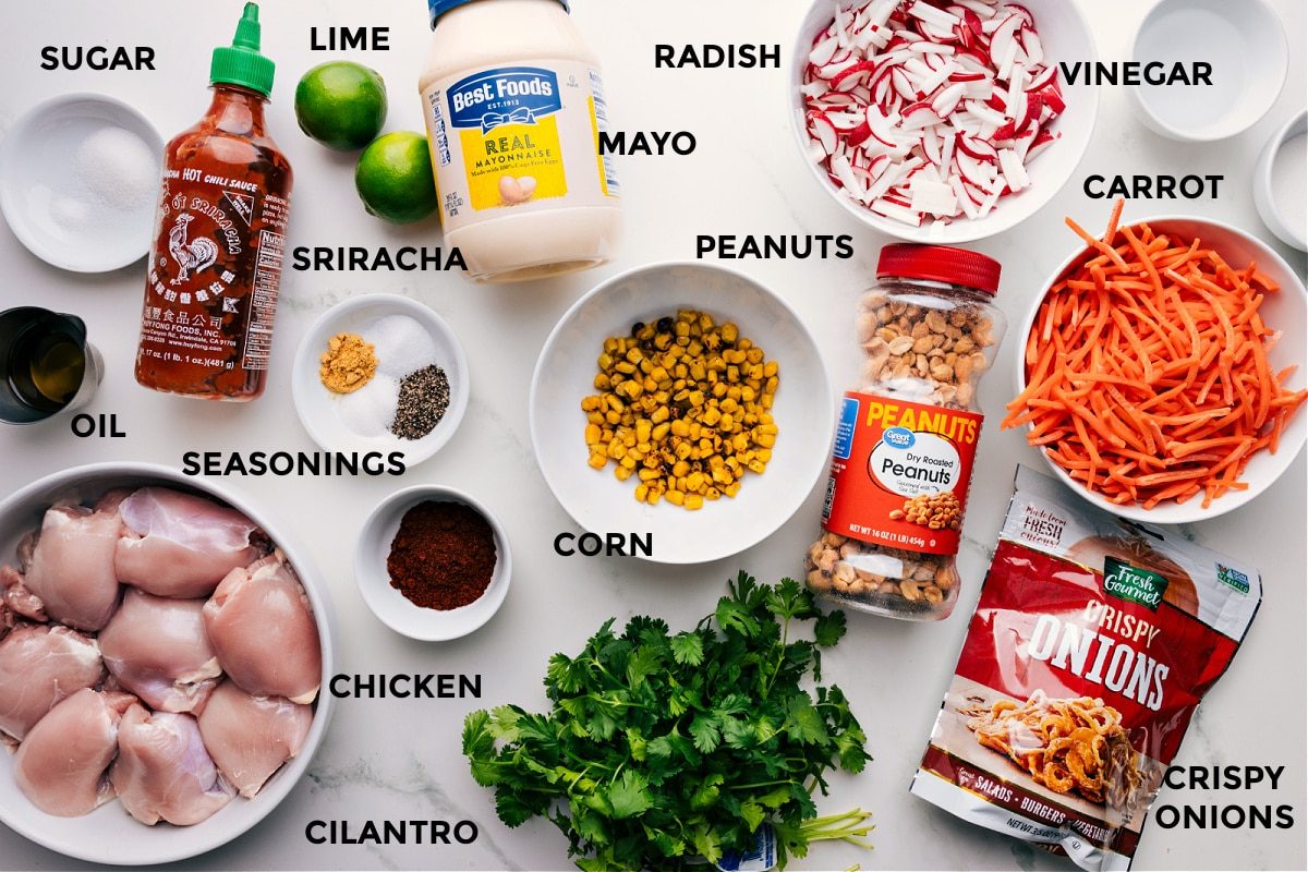 All ingredients prepped for straightforward assembly: sugar, sriracha, lime, mayo, radish, vinegar, carrot, peanuts, corn, seasonings, oil, meat, cilantro, and crispy onions.