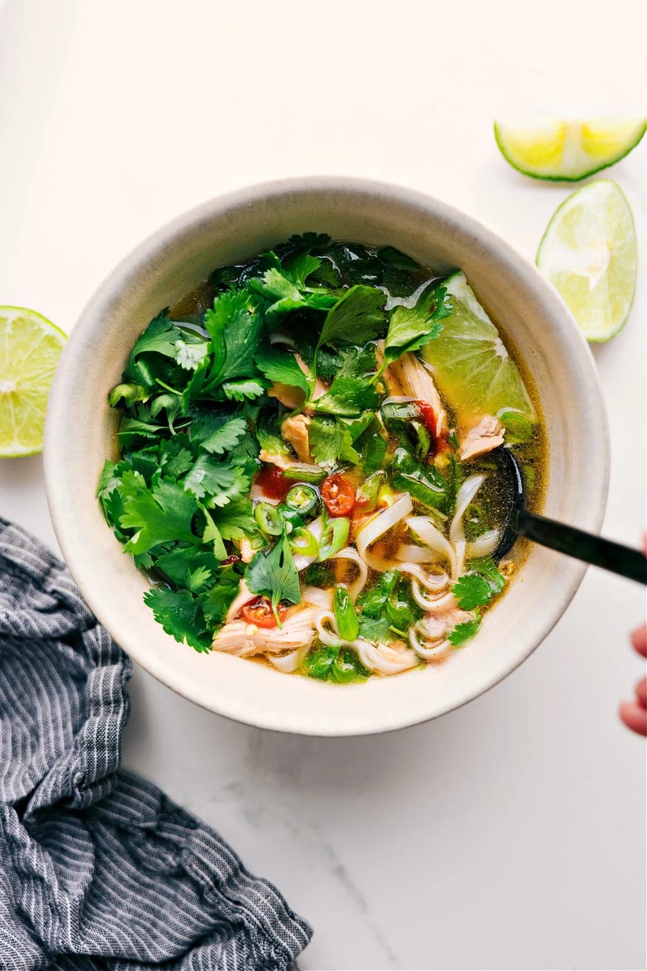 Asian chicken recipe: Chicken pho recipe in a bowl with tons of fresh herbs in it.