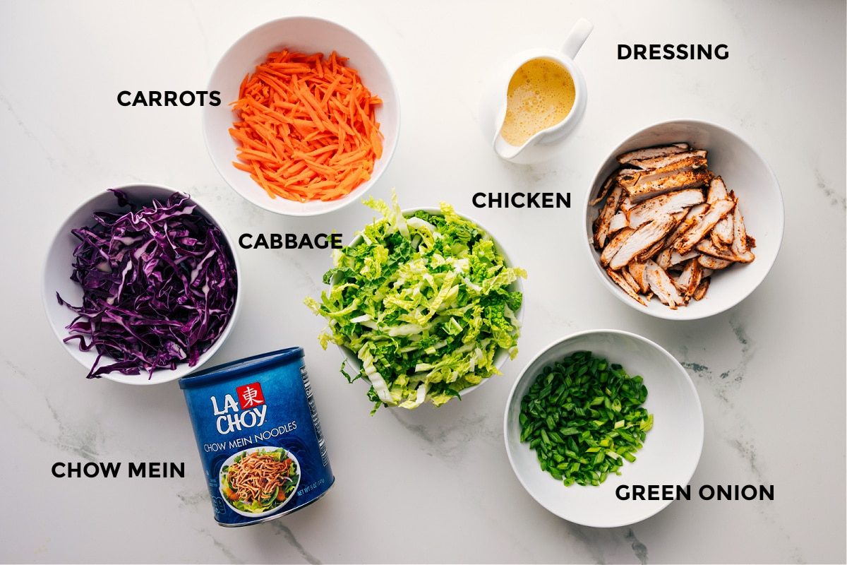 All the ingredients in this recipe prepped out for straightforward assembly including the cabbage, carrots, chow mein, chicken, dressing, and green onions.