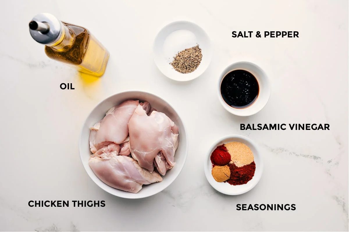 All the ingredients in this recipe prepped out for straightforward assembly including the oil, thighs, seasonings, and balsamic vinegar.