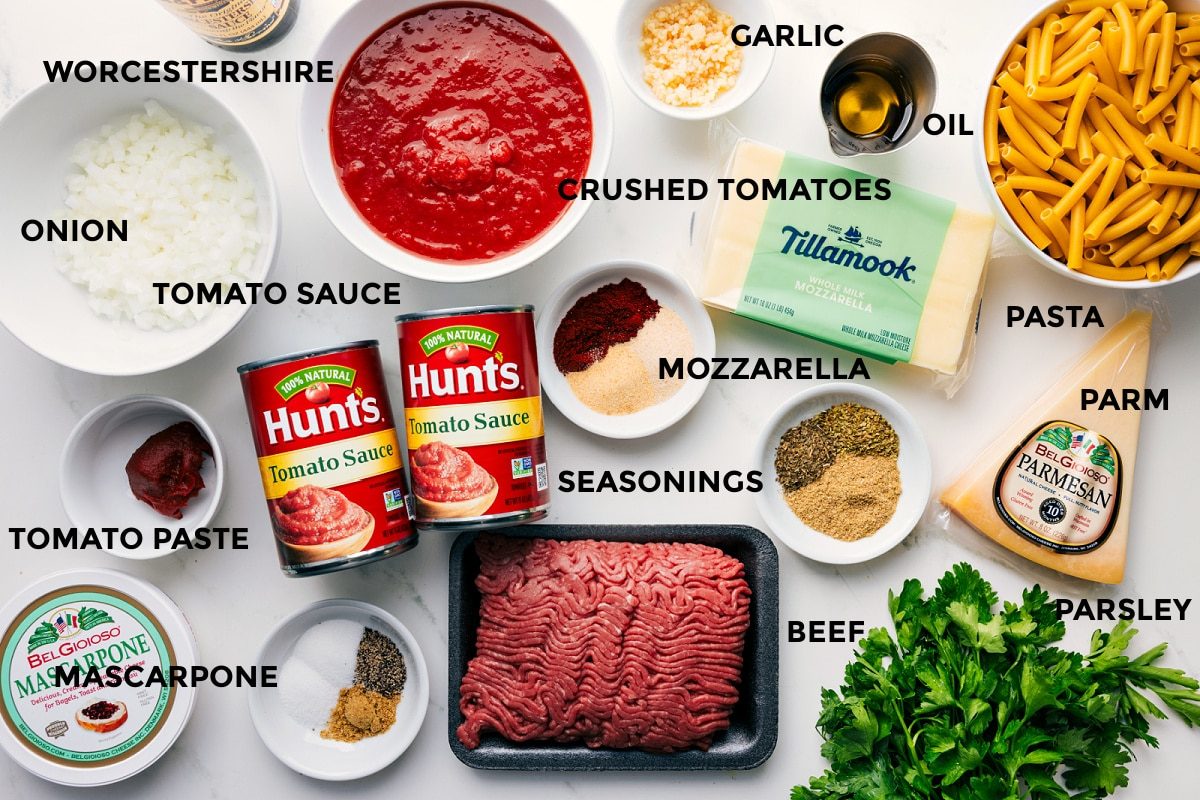 All the ingredients in this recipe prepped out for straightforward assembly including Worcestershire sauce, onion, tomato sauce, tomato paste, mascarpone, seasonings, ground beef, mozzarella, parsley, Parmesan, pasta, olive oil, garlic, and crushed tomatoes.