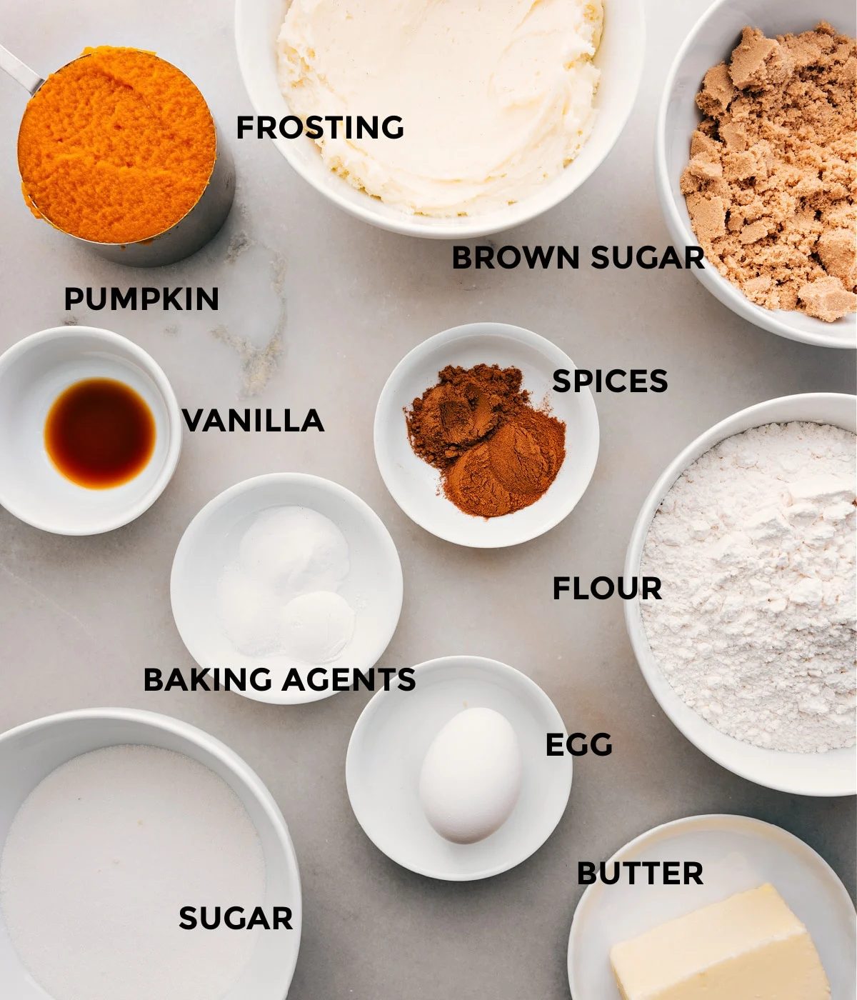 This recipe's ingredients—sugar, spices, flour, baking agents, egg, butter, vanilla, and pumpkin—are prepped for straightforward assembly.