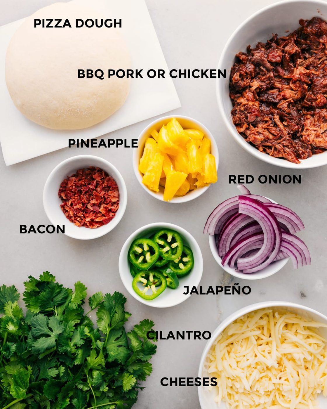 All the ingredients for this recipe are prepped for straightforward assembly, including the dough, meat, pineapple, red onion, jalapeno, cheese, and cilantro.