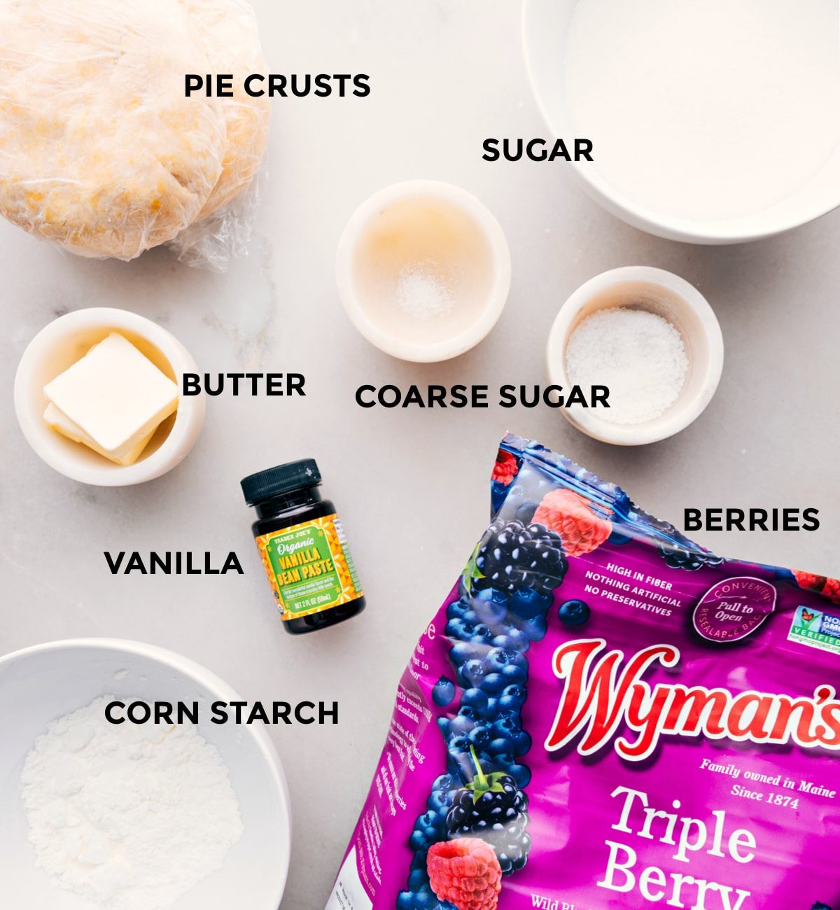 All the ingredients for this recipe prepped out for straightforward assembly including the pie crusts, sugar, butter, vanilla, berries, and corn starch.