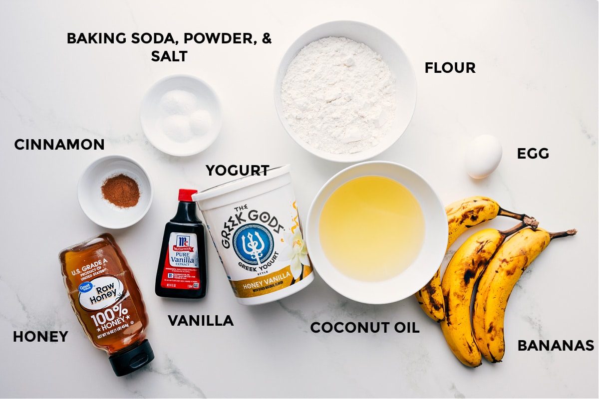All the ingredients in this recipe prepped out for straightforward assembly including the honey, cinnamon, baking soda, powder, salt, vanilla, yogurt, flour, coconut oil, egg, and bananas.