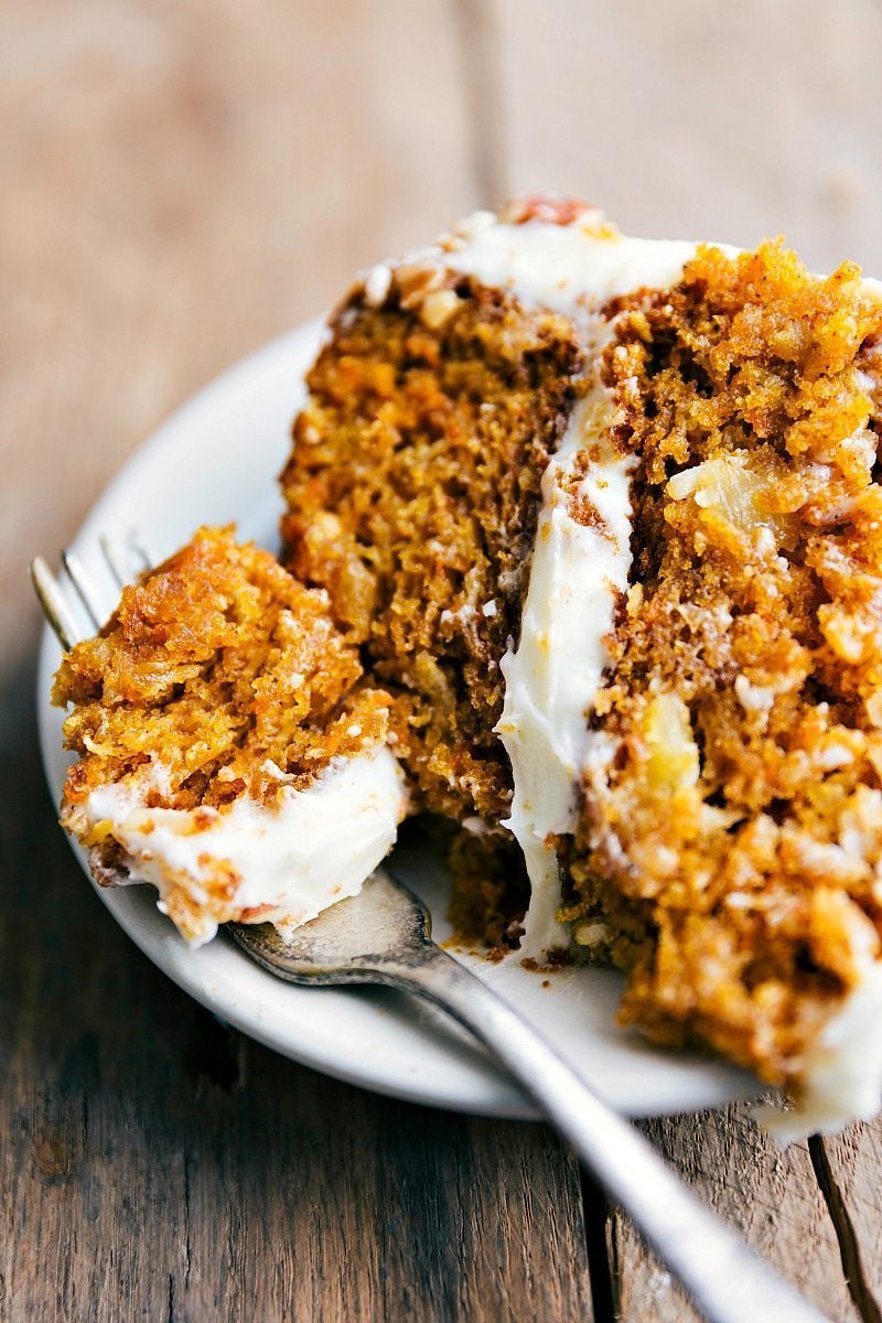 A slice of carrot and pumpkin cake with a bite taken out of it, packed full of flavor and evenly complemented by the icing.