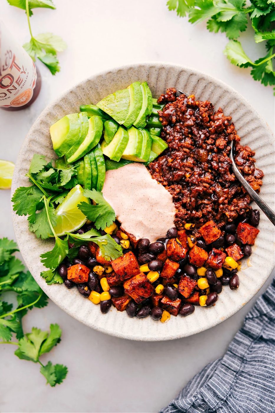 Ground beef taco bowl with sweet potatoes, avocado, and creamy sauce.