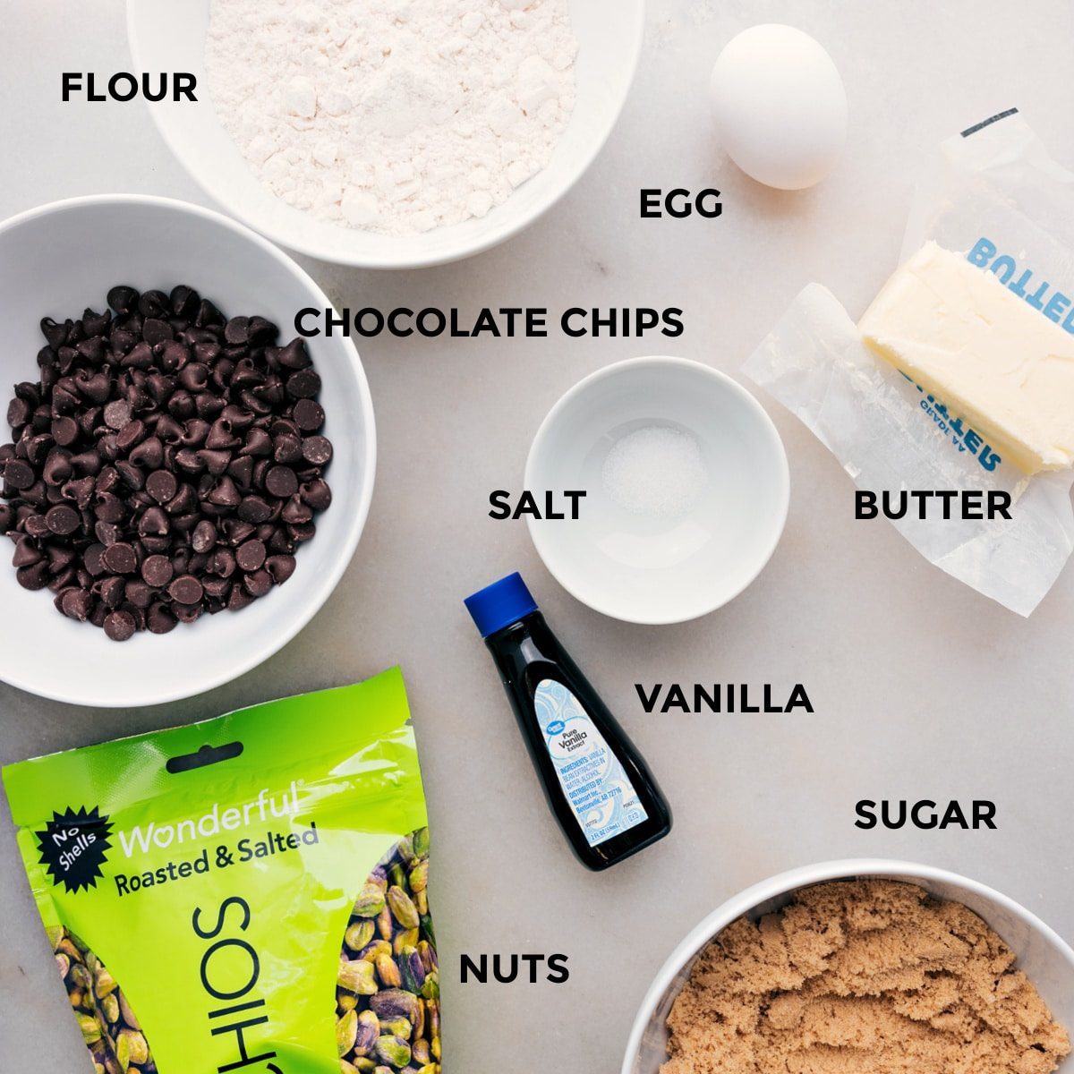 All the ingredients including flour, salt, butter, vanilla, sugar, pistachios, chocolate chips, and an egg prepped out for straightforward assembly.