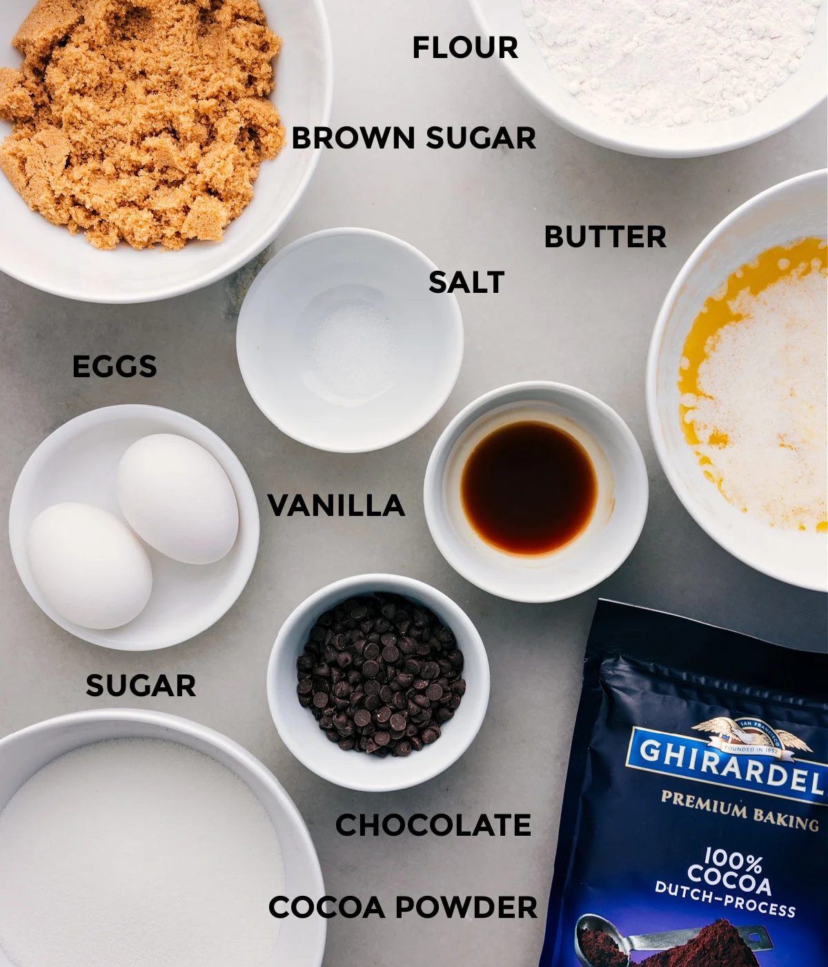 All the ingredients—butter, salt, flour, eggs, vanilla, cocoa powder, chocolate, and sugar—are prepped for straightforward assembly.