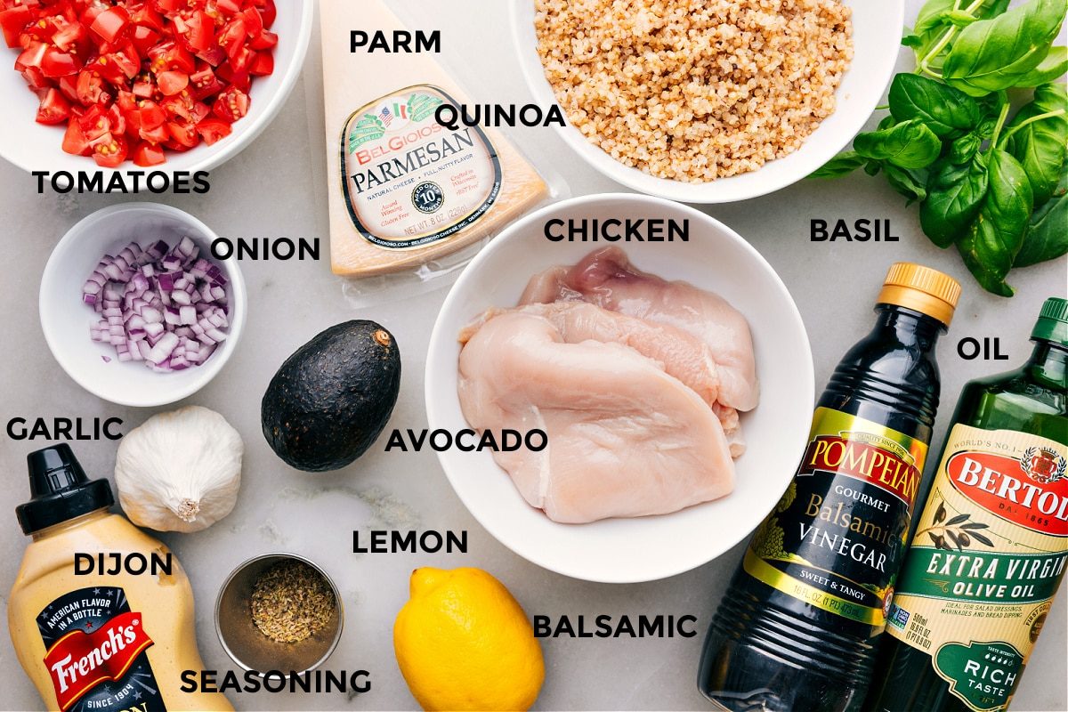 All the ingredients are prepped for straightforward assembly—tomatoes, Parmesan, quinoa, basil, chicken, avocado, onion, garlic, Dijon, lemon, balsamic, and seasonings.
