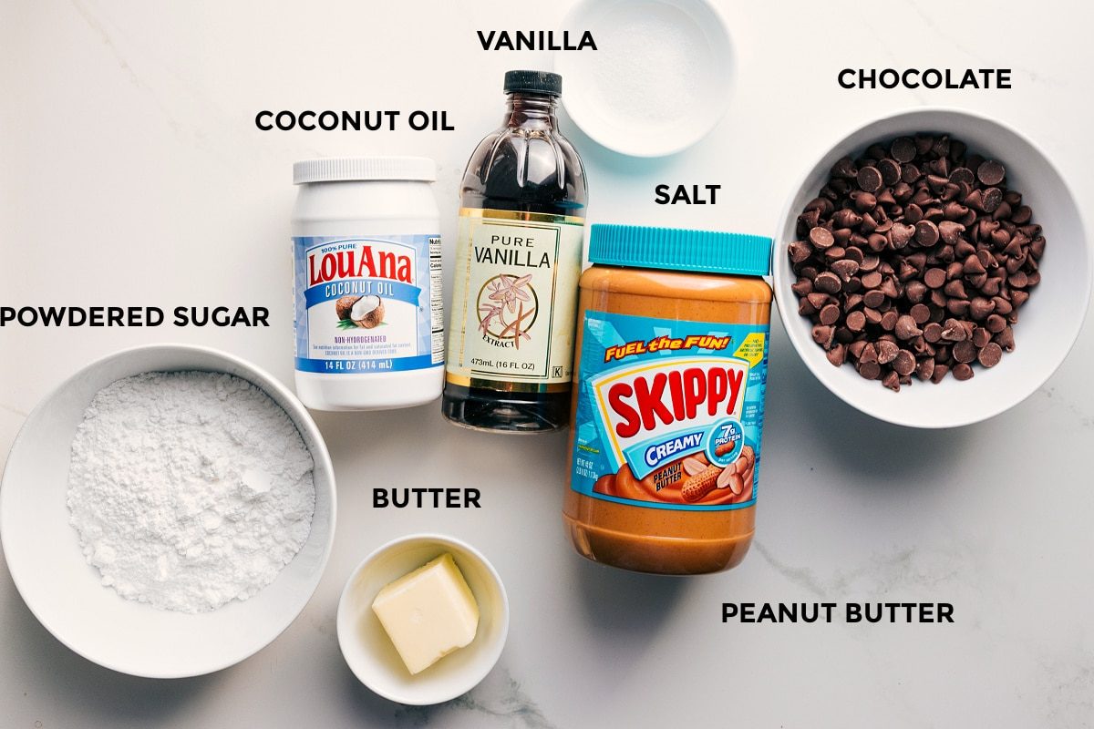 Ingredients in this recipe prepped out for straightforward assembly including powdered sugar, coconut oil, vanilla, butter, salt, peanut butter, and chocolate.