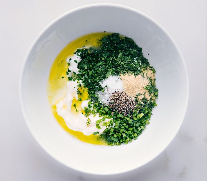 The olive oil being added into the bowl with all the other ingredients for this buttermilk ranch dressing recipe.