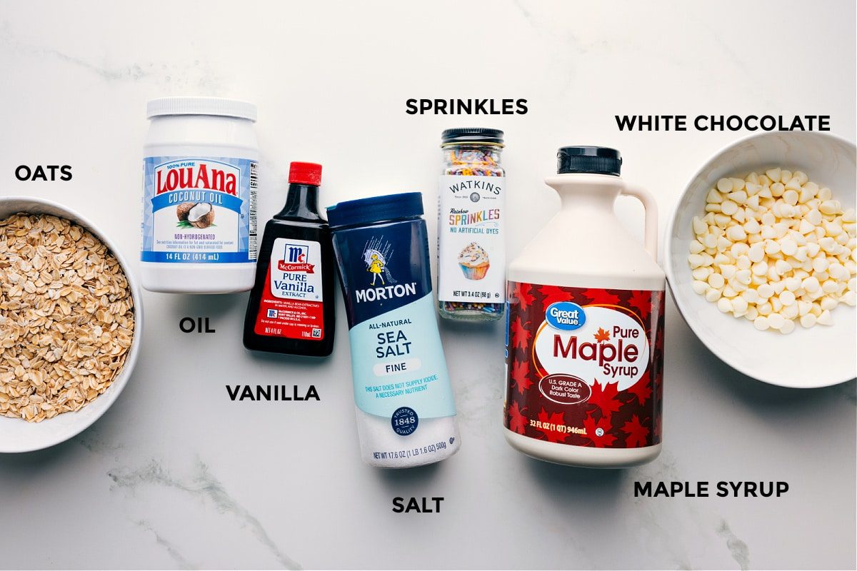 Ingredients in this recipe prepped out for straightforward assembly including the oats, oil, vanilla, salt, sprinkles, maple syrup, and white chocolate.
