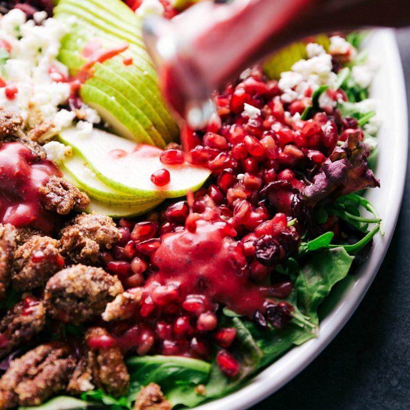 Dressing being poured over the pomegranates, ready to be mixed in with the rest of the ingredients.