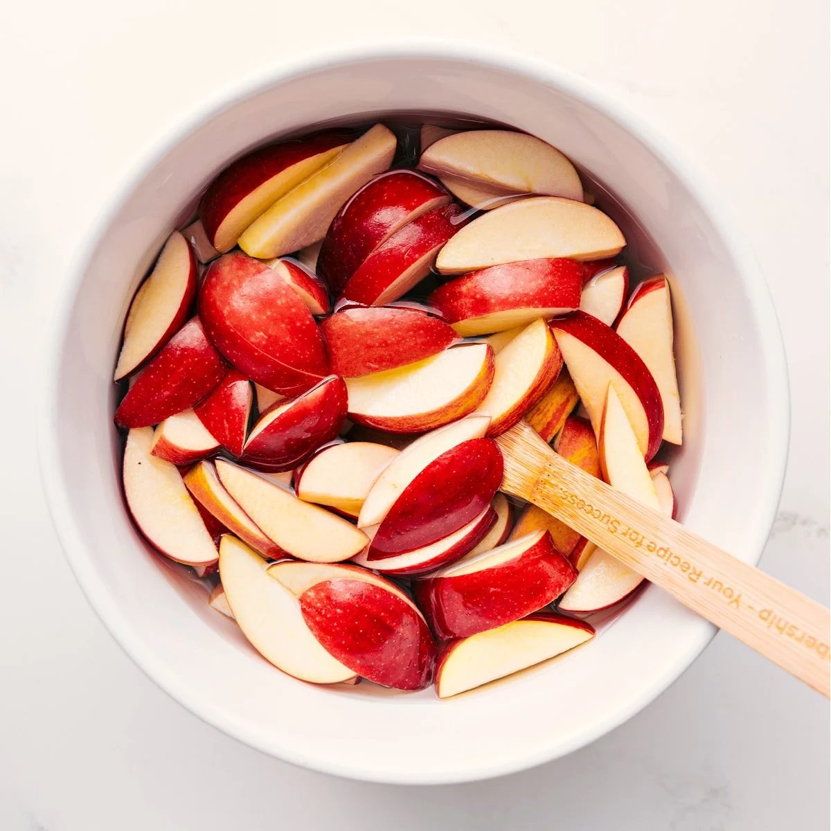 Apple slices soaking in salted water to prevent browning for Caramel Apple Dessert Cups.