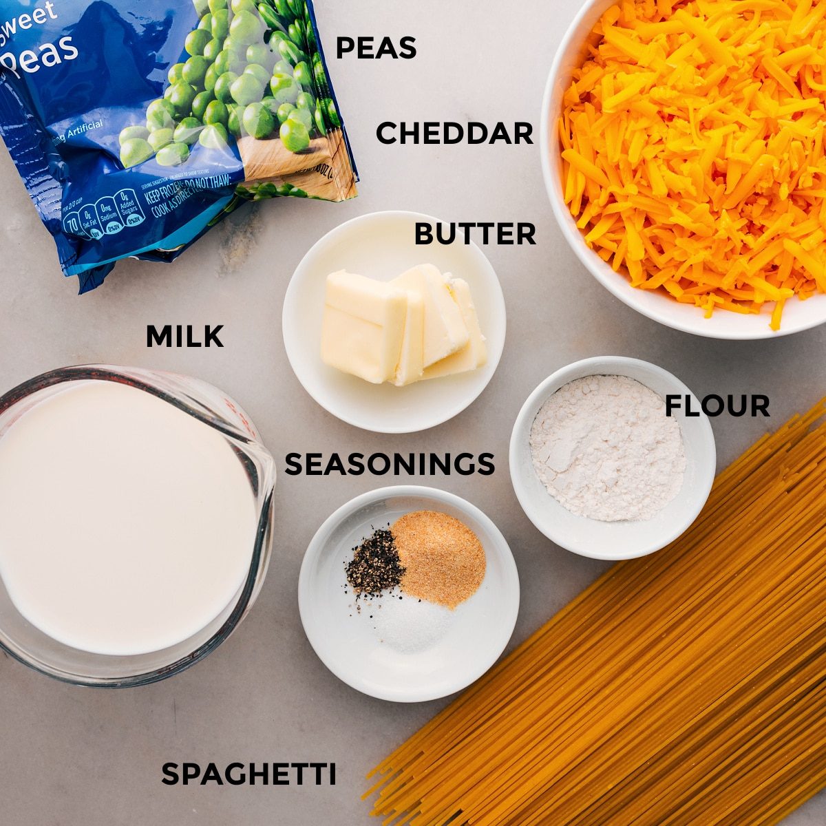 This recipe's ingredients are prepped for straightforward assembly: pasta, flour, cheese, butter, peas, and milk.