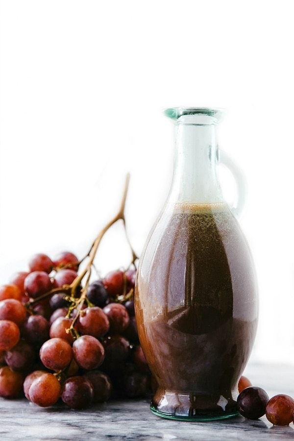 Cherry balsamic salad dressing in a container, accompanied by fresh grapes for a satisfying salad.