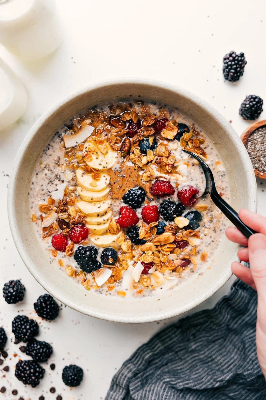 Chia Seed Overnight Oats in a bowl topped with granola, sliced banana, fresh berries, and chia seeds.