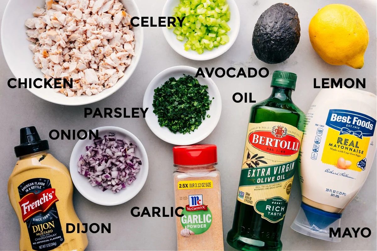 All the ingredients in this recipe prepped out for straightforward assembly including the meat, celery, avocado, parsley, onion, oil, lemon, mayo, garlic, and dijon.