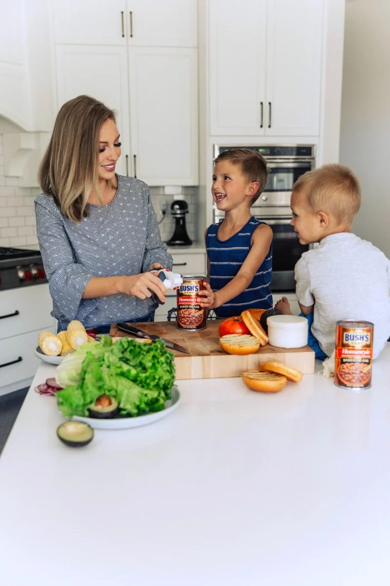 helsea alongside her boys, opening a can of baked beans, preparing to serve them as a satisfying side for their meal.