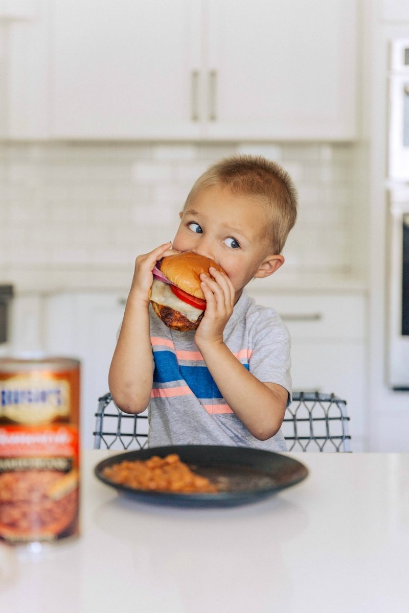One of the cook's young sons delightfully eating a finished chicken burger, a meal enjoyed by all.