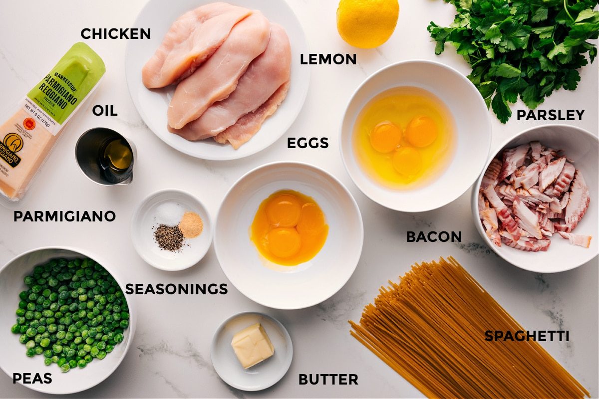 All ingredients for this recipe laid out, including chicken, bacon, eggs, spaghetti, parmesan, peas, and lemon.