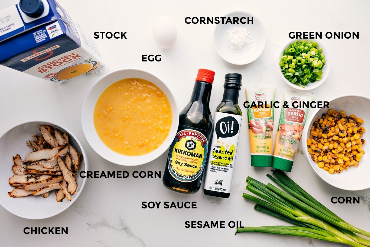 All the ingredients in this recipe prepped out for straightforward assembly including the stock, chicken, creamed corn, soy sauce, sesame oil, cornstarch, sesame oil, garlic, ginger, green onions, and corn.