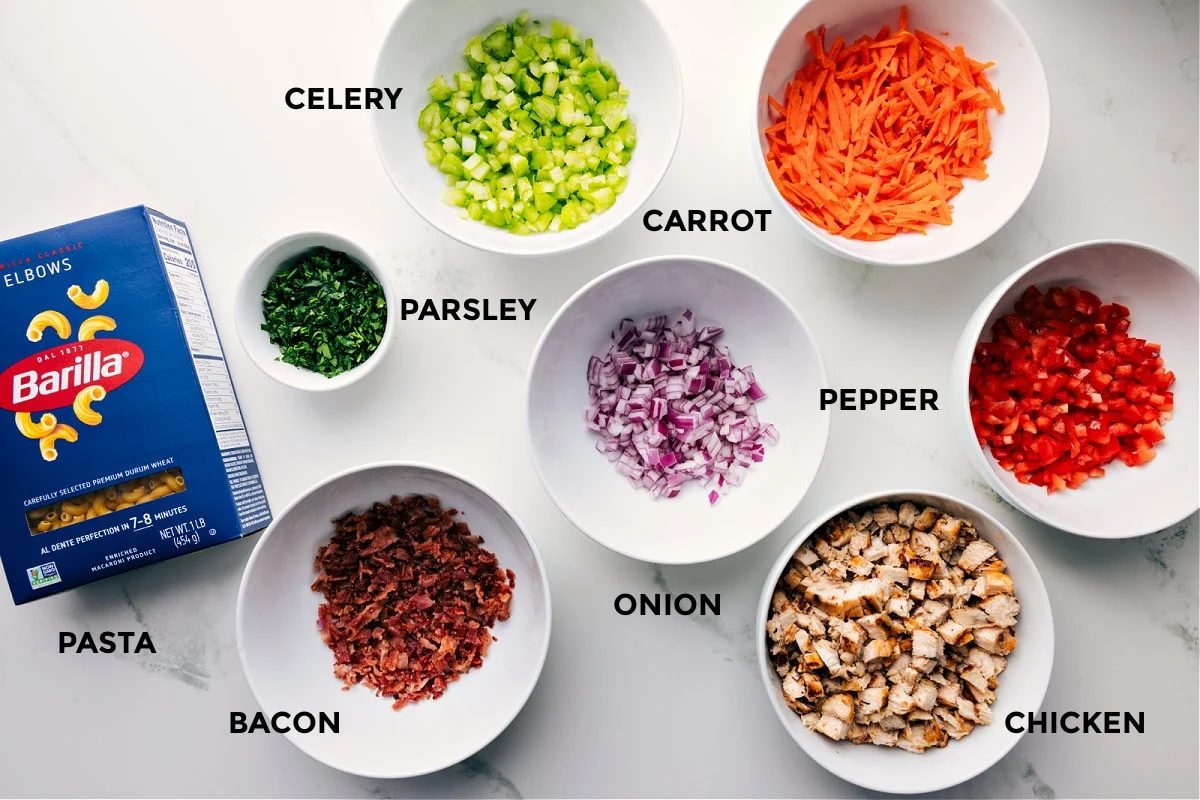 Ingredients in this recipe prepped out for straightforward assembly including the pasta, parsley, celery, carrot, onion, pepper, chicken, and bacon.