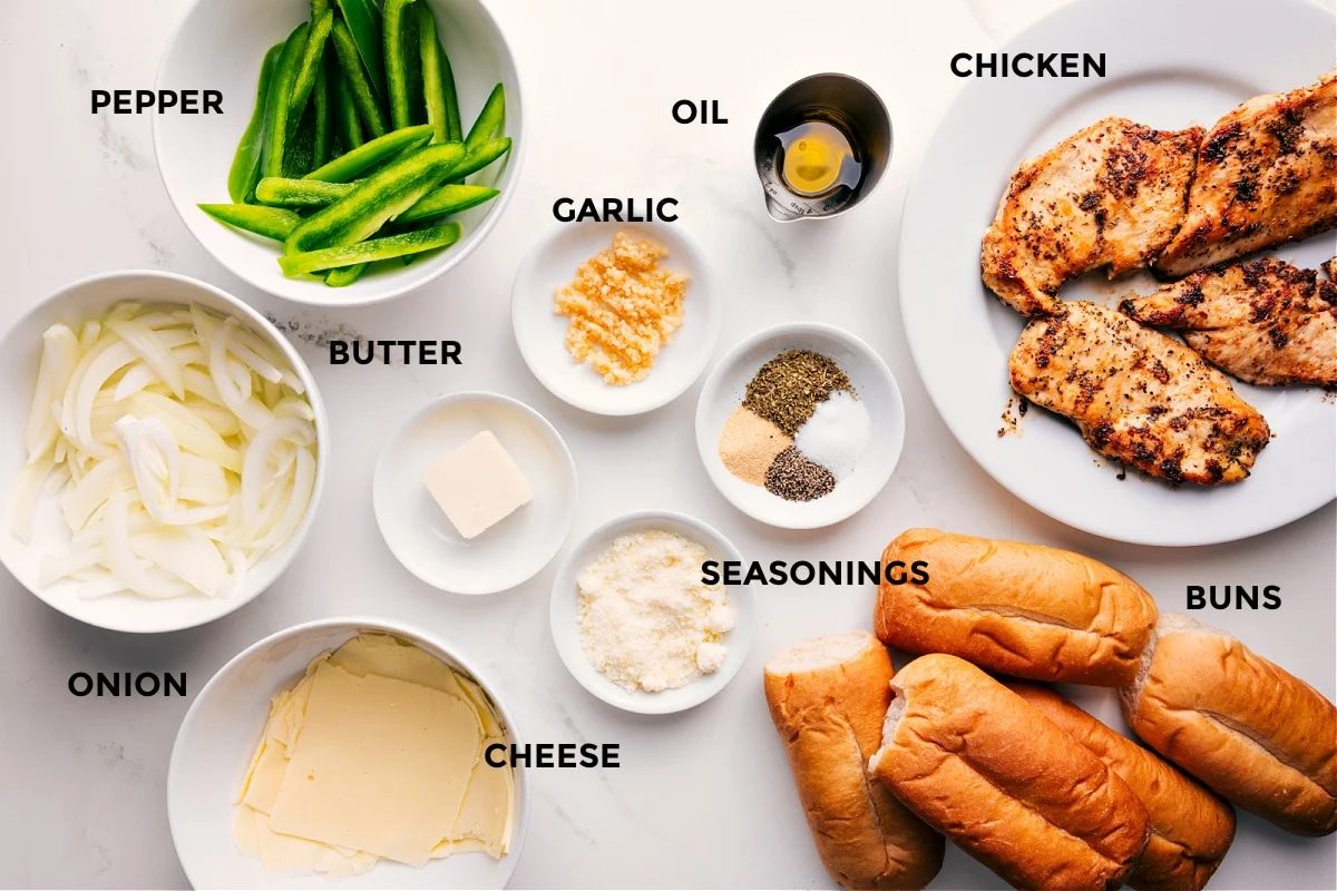 All the ingredients in this recipe prepped out for straightforward assembly including the onions, cheese, peppers, butter, seasonings, garlic, oil, buns, and chicken.