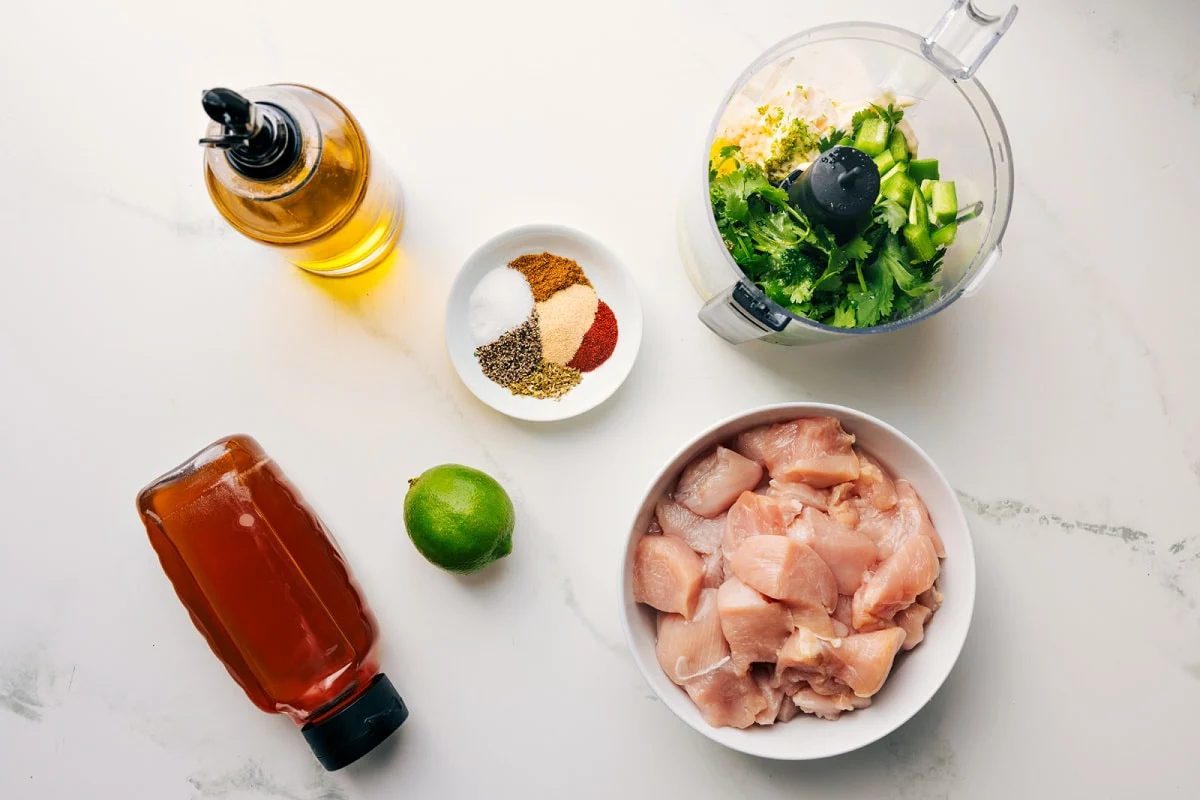 All the ingredients in this recipe prepped out for straightforward assembly including the honey, oil, lime, seasonings, chicken, and sauce.