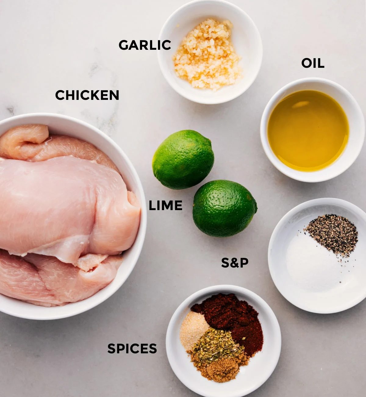 All the ingredients prepped for straightforward assembly, including oil, spices, lime, garlic, and chicken.