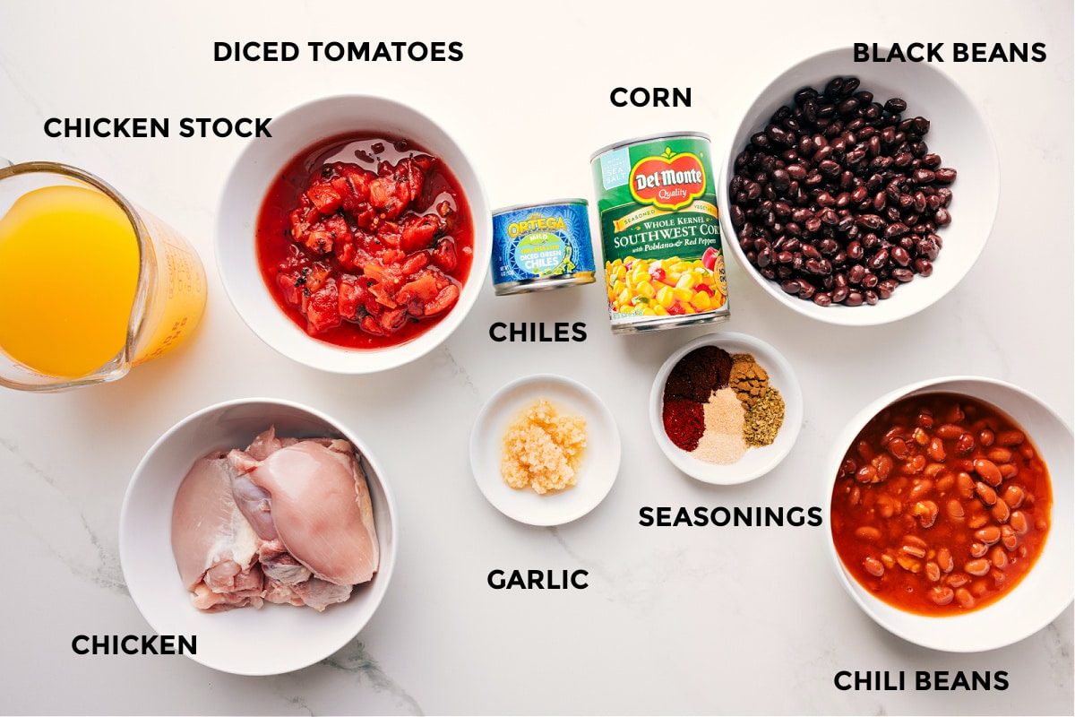All the ingredients for Chicken Taco Soup prepped for straightforward assembly, including stock, chicken, tomatoes, chiles, corn, garlic, seasonings, black beans, and chili beans.