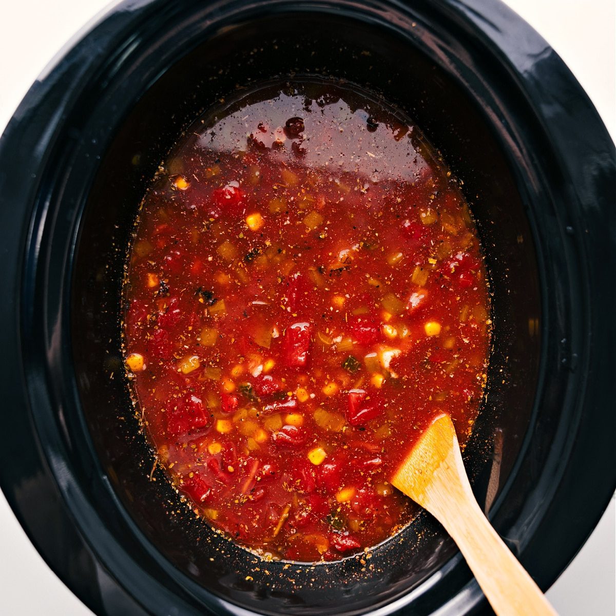 All the ingredients for chicken taco soup all dumped in a slow cooker to slow cook.