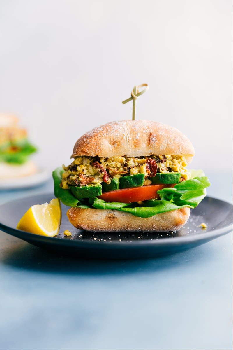 Chickpea recipes: pesto chickpea sandwich on ciabatta with tomatoes, avocado, and lettuce inside.