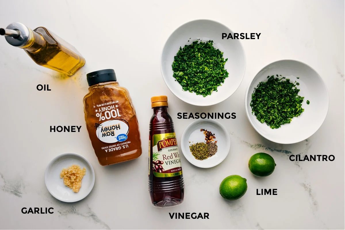 Ingredients prepped for straightforward assembly, including oil, honey, garlic, seasonings, parsley, cilantro, limes, and vinegar.
