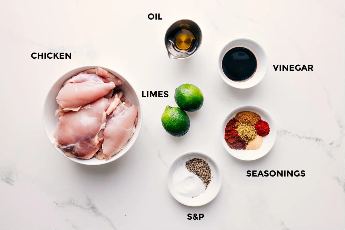 All the ingredients in this recipe prepped out for straightforward assembly including the chicken, limes, oil, vinegar, and seasonings.