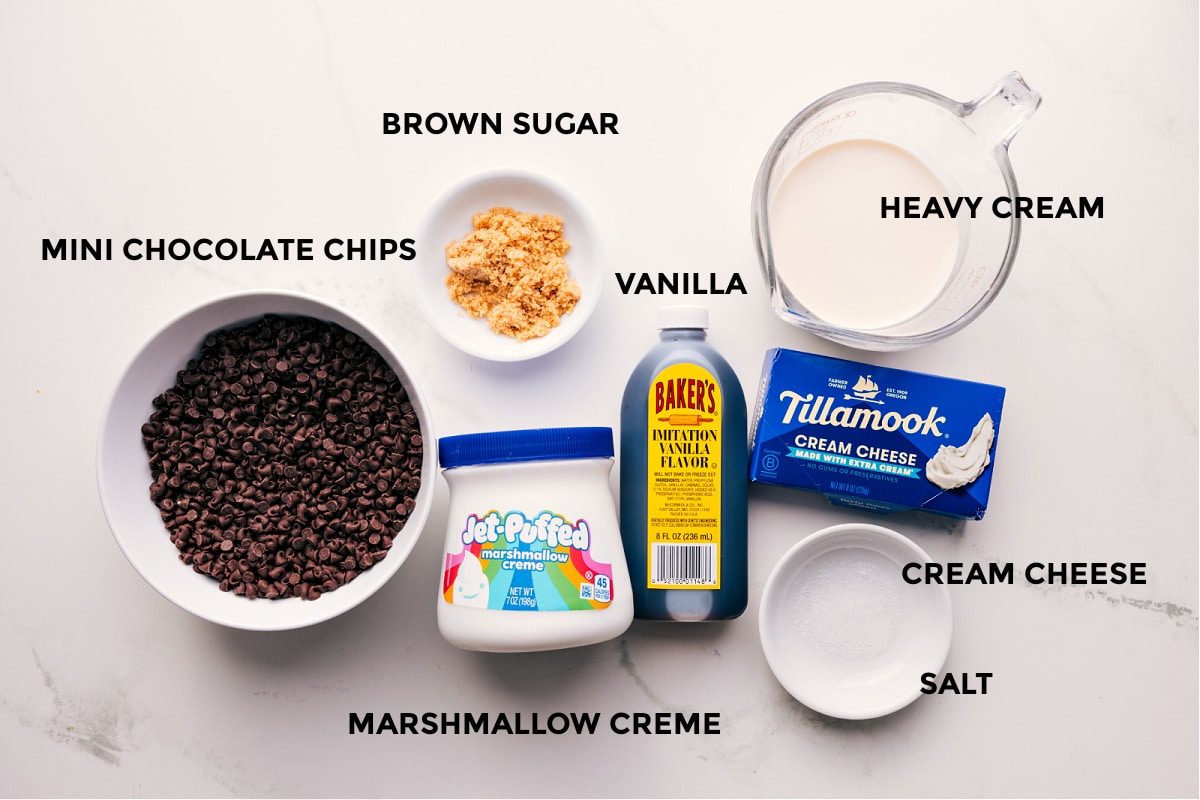 All the ingredients in this recipe prepped out for straightforward assembly including the chocolate, marshmallow creme, cream cheese, salt, vanilla, heavy cream, and brown sugar.