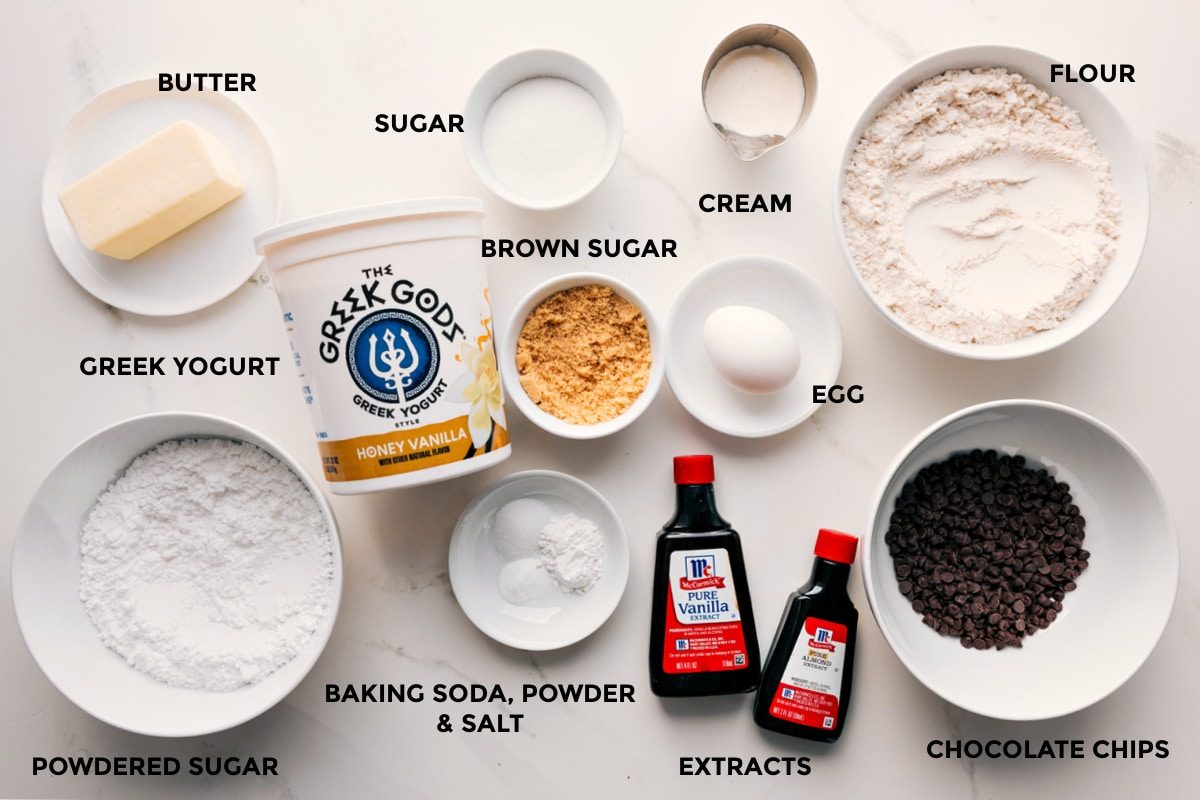 All the ingredients for this recipe prepped and ready for straightforward assembly, including butter, powdered sugar, white sugar, brown sugar, yogurt, baking agents, cream, egg, extracts, and chocolate chips.