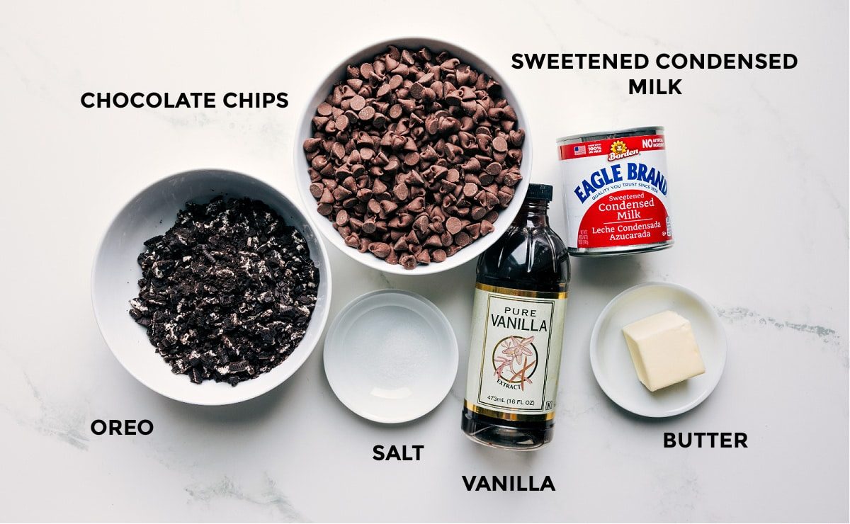 All the ingredients in this recipe prepped out including the crushed Oreos, chocolate chips, sweetened condensed milk, salt, vanilla, and butter.
