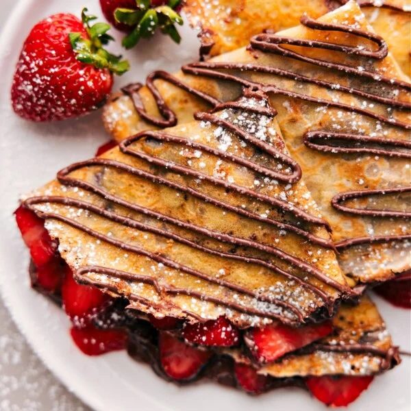 The finished dessert of warm Nutella crepes expertly cooked to achieve the reliable texture, filled with fresh strawberries and Nutella.