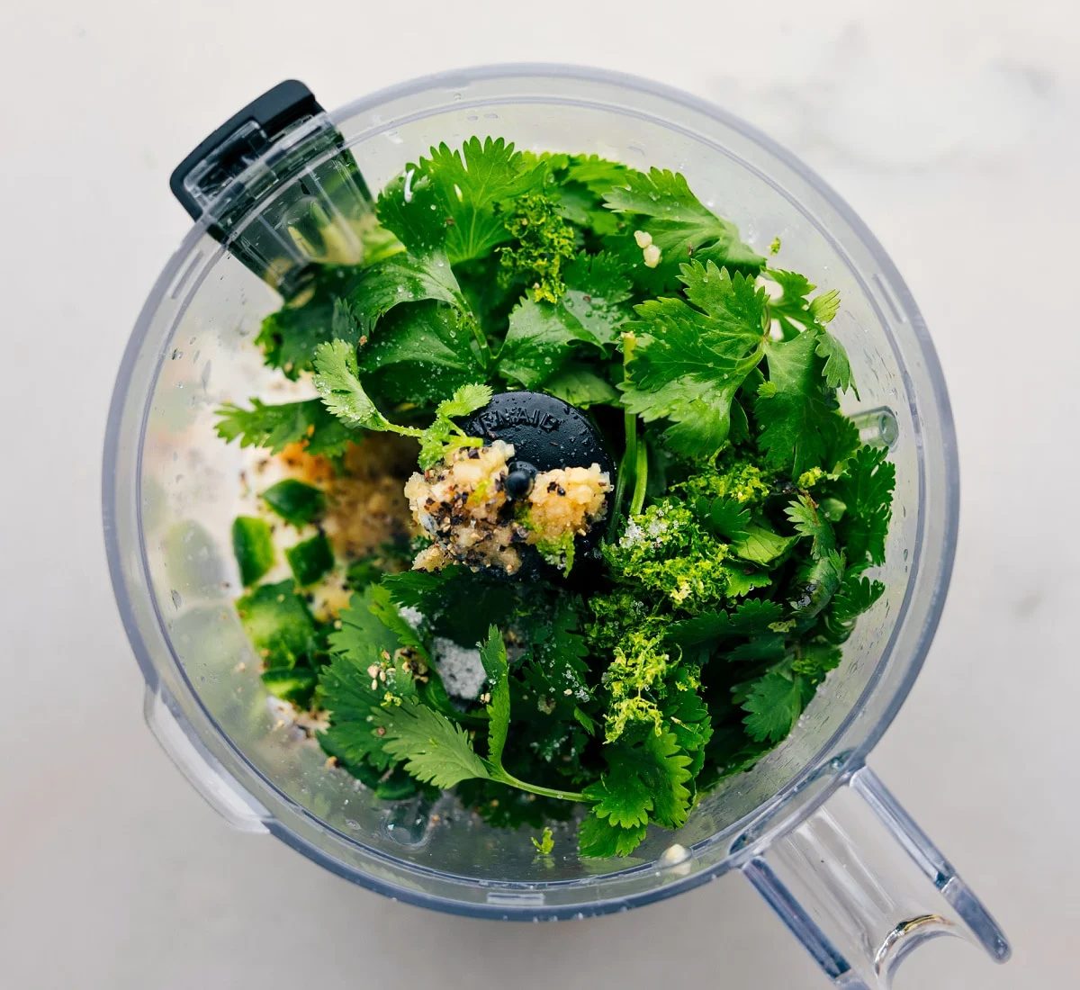 All the ingredients in the cilantro lime sauce being added to a food processor.