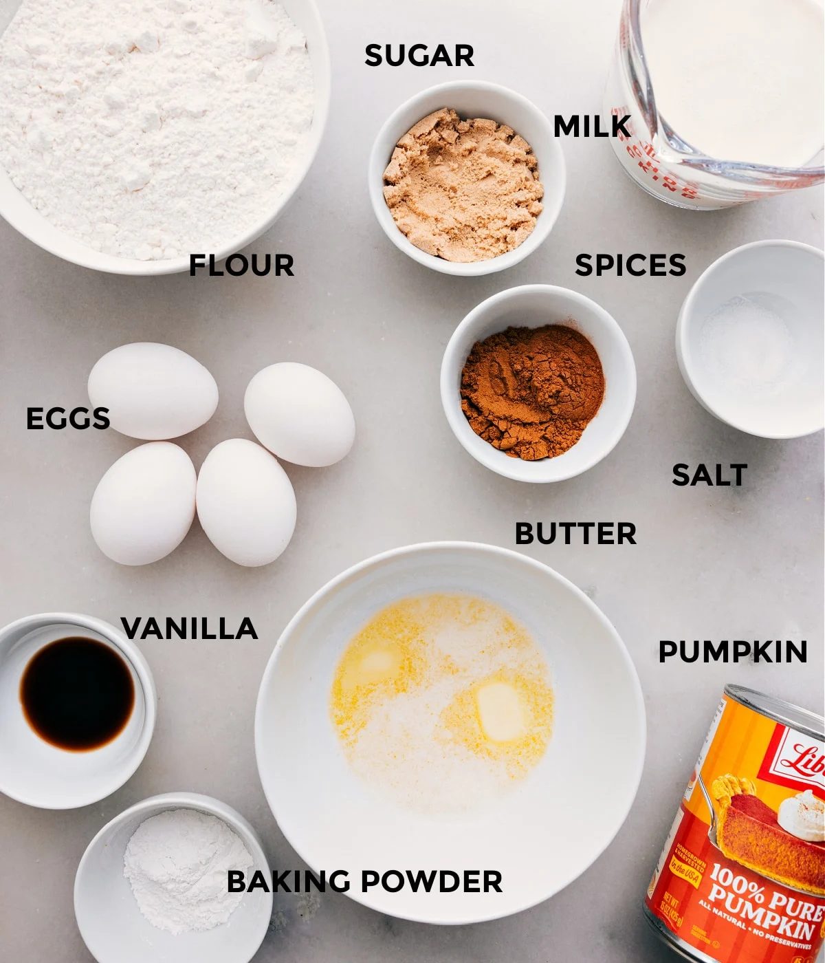 All the ingredients in this recipe are prepped for straightforward assembly, including sugar, milk, spices, salt, butter, eggs, flour, baking powder, vanilla, and cocoa powder.